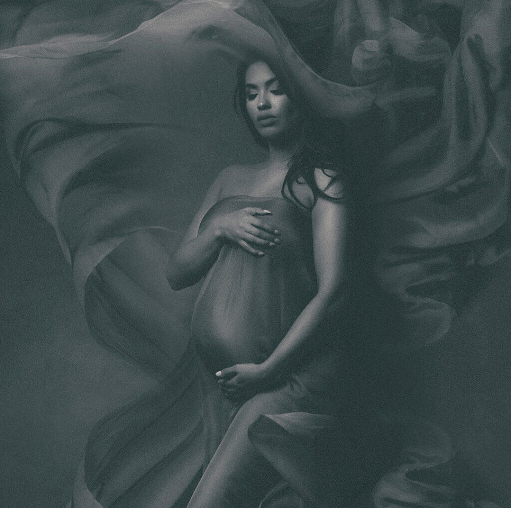 The editorial photo captures the elegant, dramatic movement of Italian silk billowing in all directions around a pregnant woman in Chicago. The photo was taken at a photography studio in Chicago, showcasing the graceful and ethereal beauty of the moment.